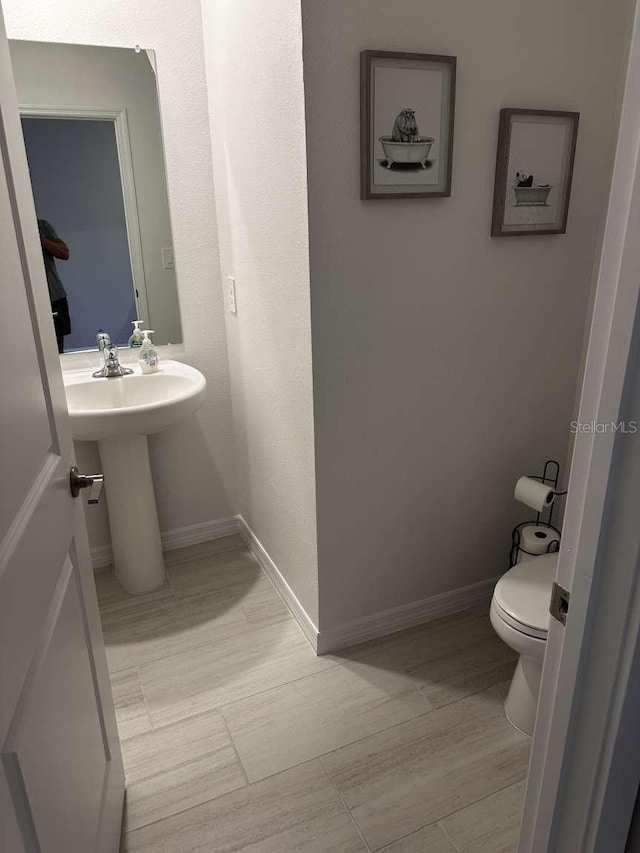 bathroom featuring baseboards and toilet