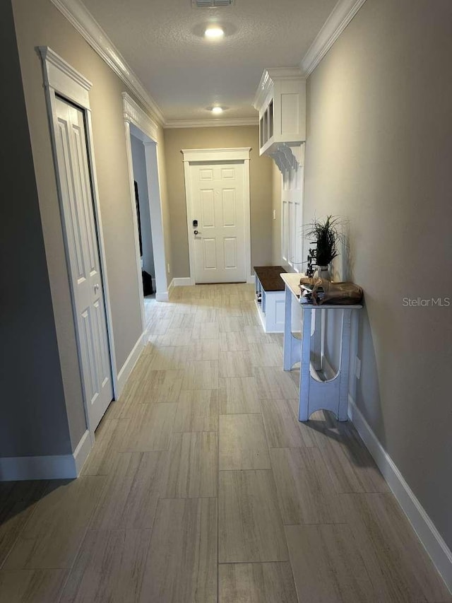 corridor featuring visible vents, crown molding, and baseboards