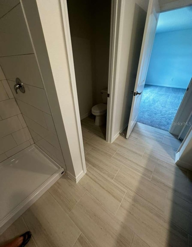 bathroom with baseboards, toilet, and a shower stall