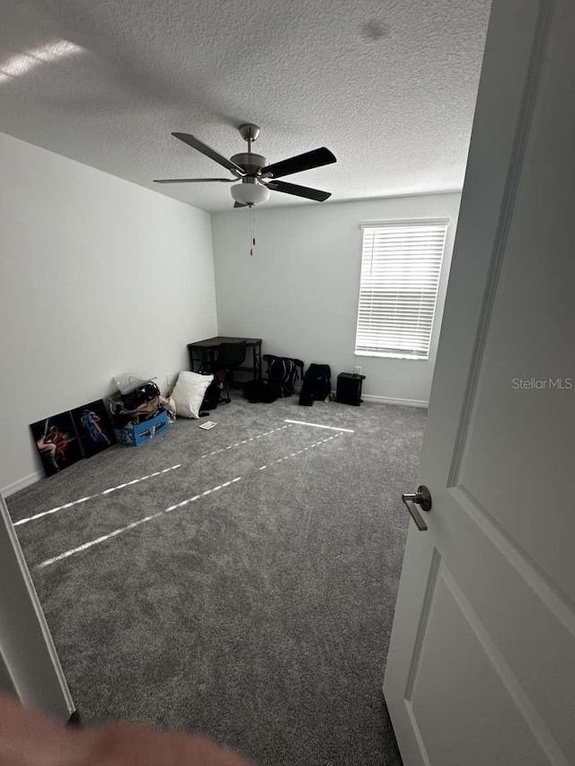 carpeted bedroom featuring a textured ceiling and a ceiling fan