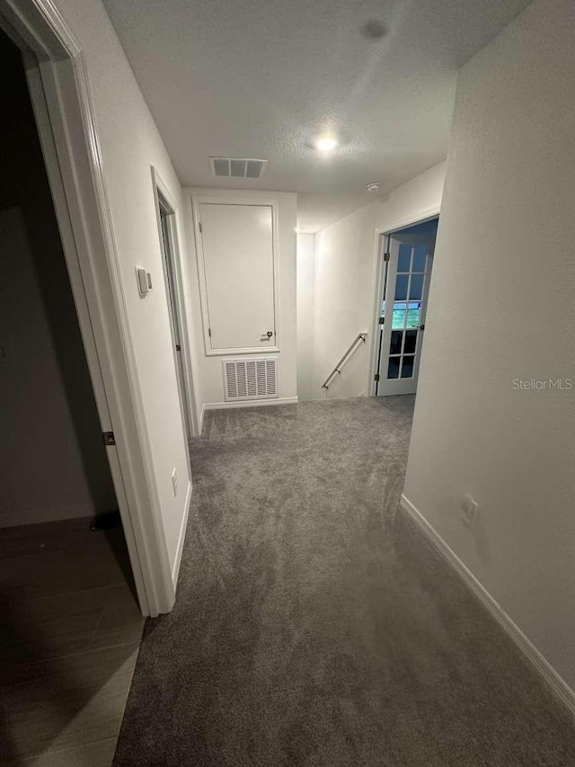 hallway with visible vents, an upstairs landing, carpet, and baseboards