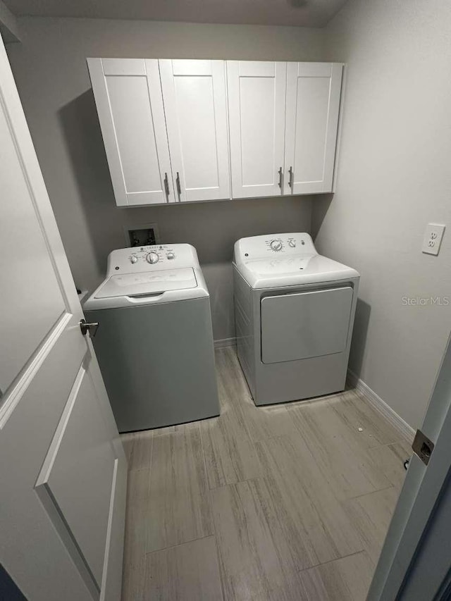 washroom featuring baseboards, cabinet space, and washer and clothes dryer