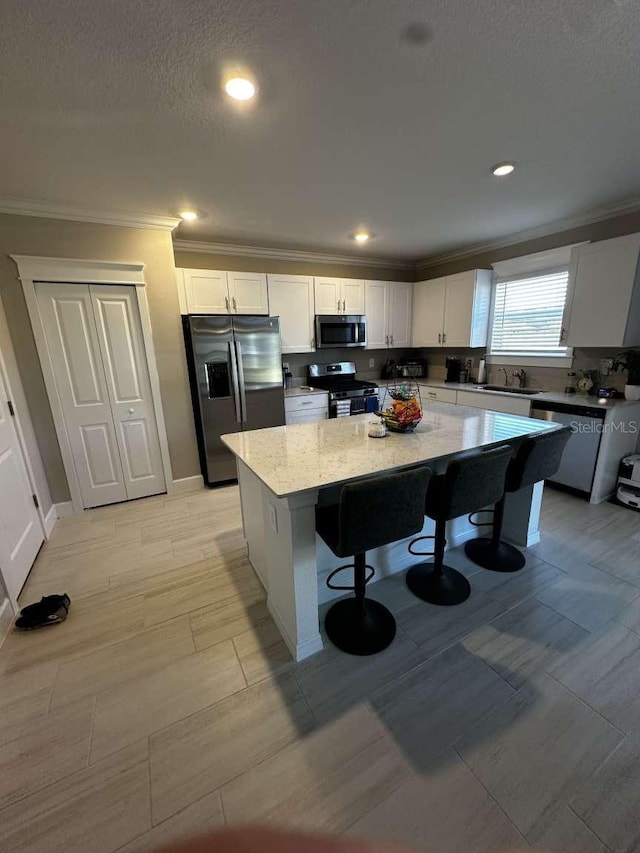 kitchen featuring white cabinets, appliances with stainless steel finishes, a center island, and a kitchen breakfast bar