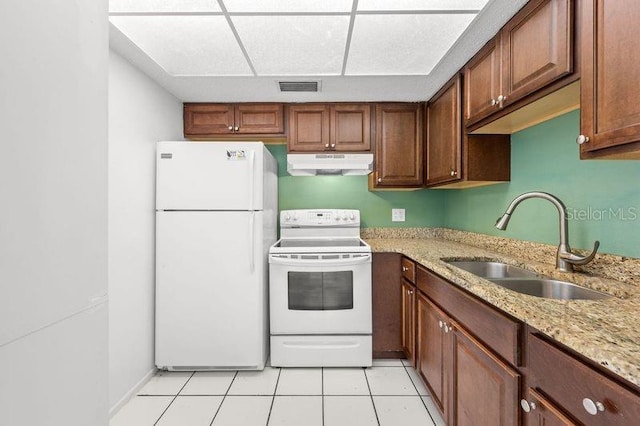 kitchen with white appliances, visible vents, light stone countertops, under cabinet range hood, and a sink