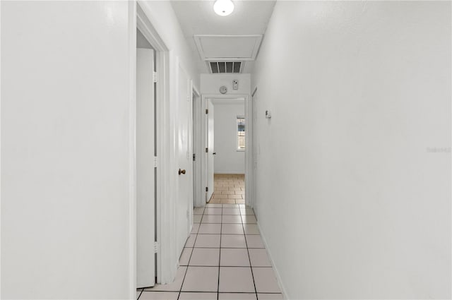 hall featuring attic access, visible vents, a textured ceiling, and light tile patterned floors