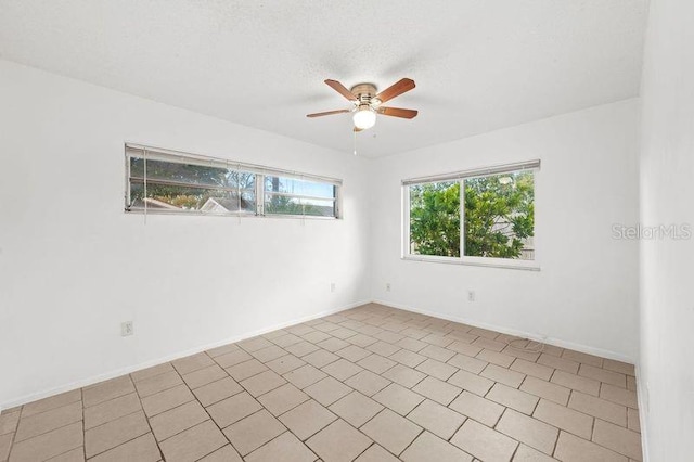 empty room with a ceiling fan, a textured ceiling, and baseboards