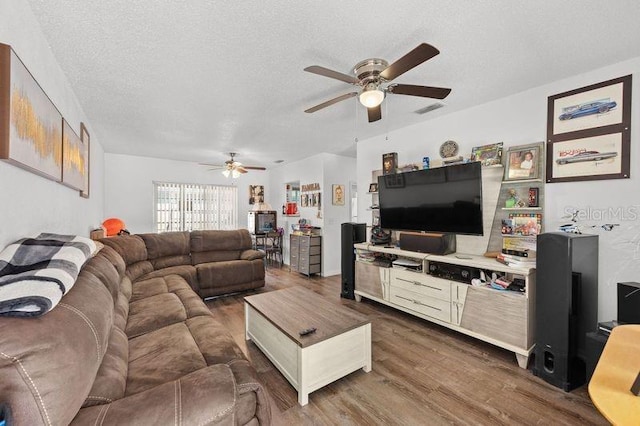 living area featuring a ceiling fan, dark wood-style flooring, visible vents, and a textured ceiling