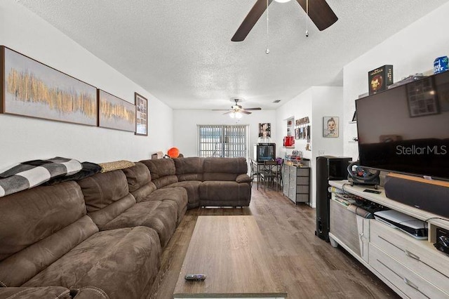 living room with a textured ceiling, ceiling fan, and wood finished floors