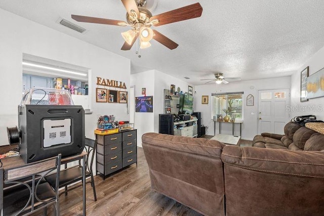 living room featuring visible vents, a textured ceiling, and wood finished floors