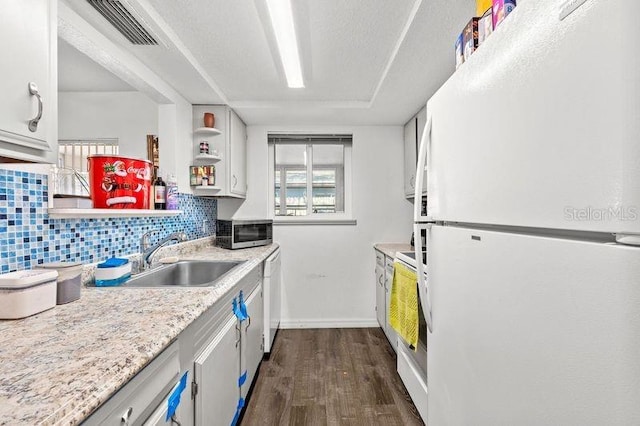 kitchen featuring white appliances, visible vents, dark wood-style flooring, light countertops, and a sink