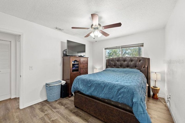 bedroom featuring visible vents, a textured ceiling, and wood finished floors