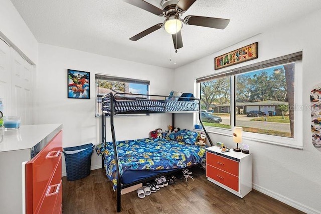 bedroom featuring ceiling fan, a textured ceiling, baseboards, and wood finished floors