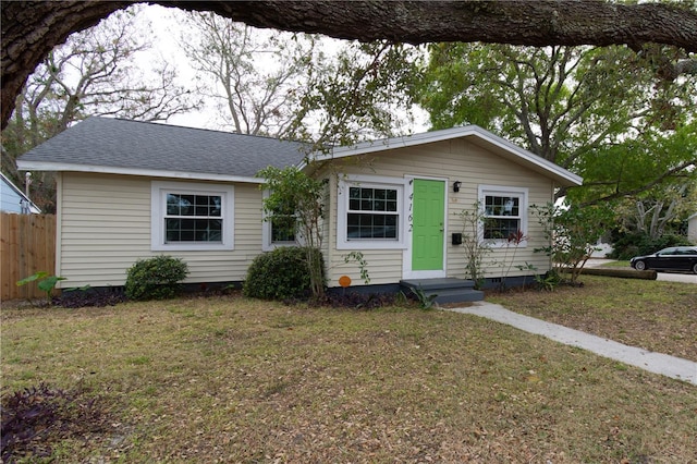 view of front of property with a shingled roof, fence, and a front lawn