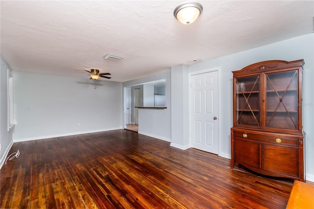 spare room featuring wood-type flooring, visible vents, a ceiling fan, a textured ceiling, and baseboards