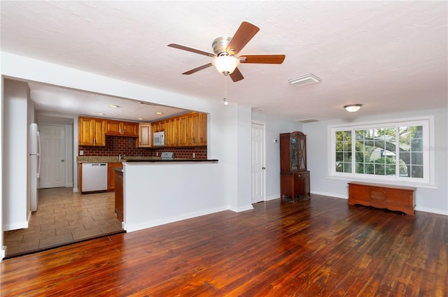 kitchen featuring white appliances, open floor plan, brown cabinets, decorative backsplash, and hardwood / wood-style floors