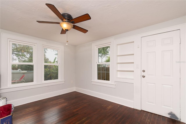 entrance foyer with a textured ceiling, plenty of natural light, dark wood finished floors, and baseboards