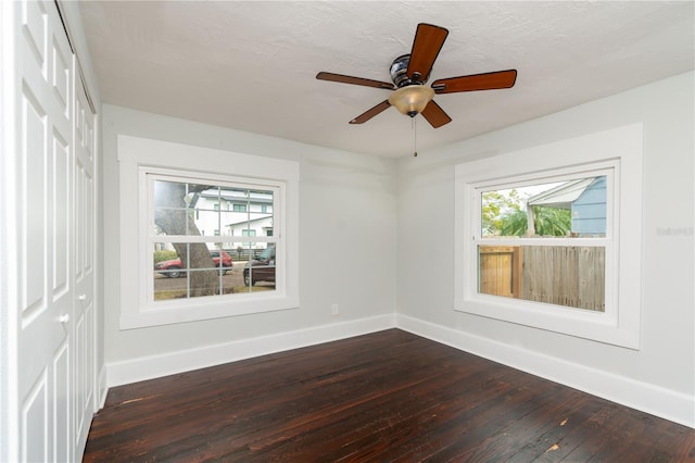 spare room with dark wood-type flooring, a wealth of natural light, and baseboards