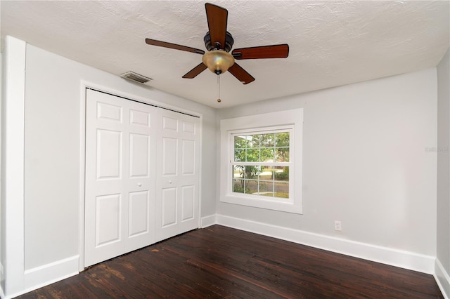 unfurnished bedroom featuring a closet, visible vents, dark wood-type flooring, a textured ceiling, and baseboards