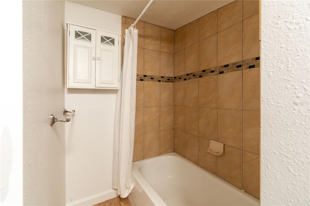 bathroom featuring shower / bath combo and baseboards