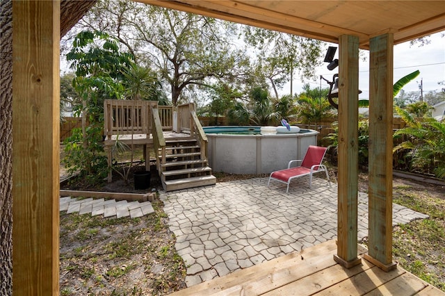 view of patio / terrace featuring fence, a wooden deck, and an outdoor pool