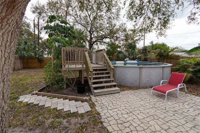 exterior space featuring a fenced backyard, a wooden deck, a fenced in pool, and a patio