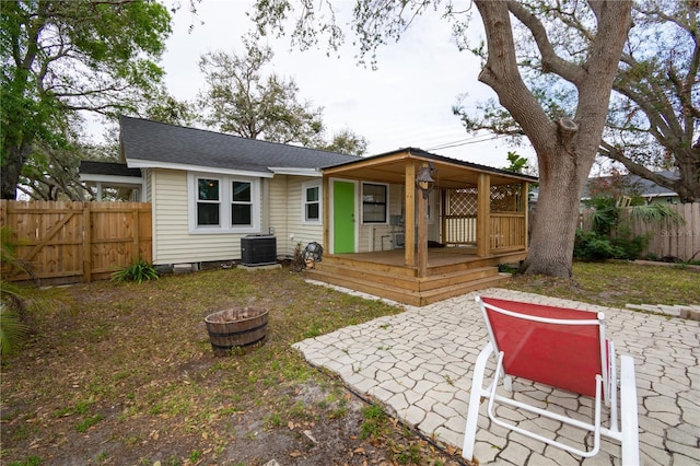 back of property featuring a shingled roof, cooling unit, and fence