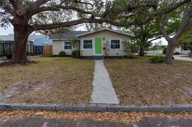 bungalow-style house with fence and a front lawn