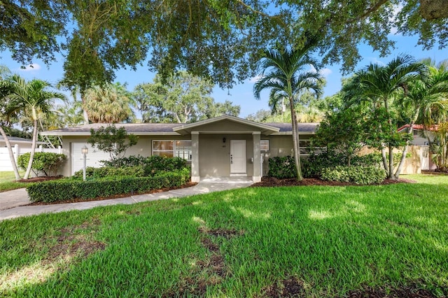 ranch-style home with a front yard, an attached garage, and stucco siding