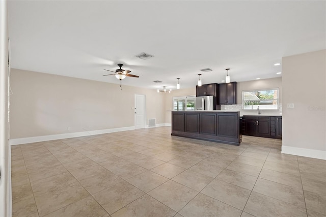 kitchen with open floor plan, dark brown cabinets, light countertops, and visible vents