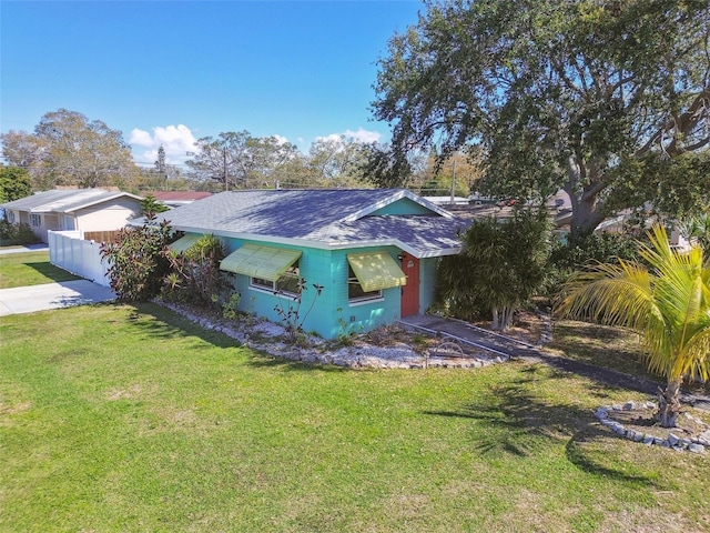 exterior space featuring a shingled roof and a front lawn