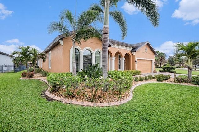 view of front of property featuring an attached garage, a front yard, fence, and stucco siding