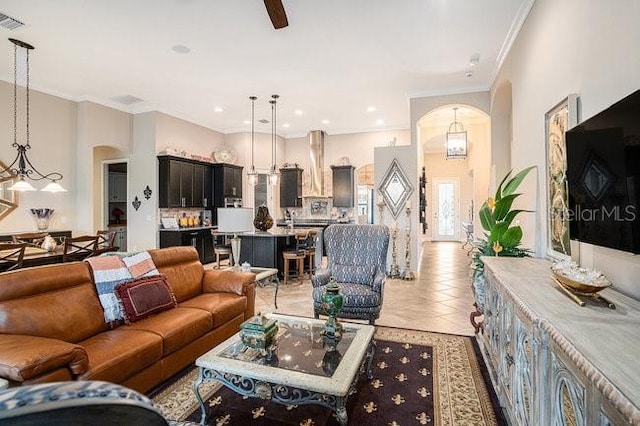 living area featuring arched walkways, light tile patterned floors, recessed lighting, visible vents, and ornamental molding