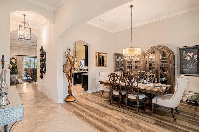 dining area featuring arched walkways, crown molding, an inviting chandelier, wood finished floors, and baseboards