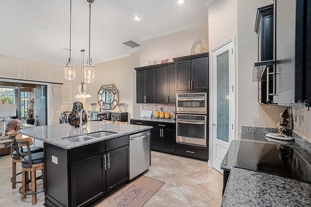 kitchen featuring light stone counters, a sink, ornamental molding, appliances with stainless steel finishes, and backsplash