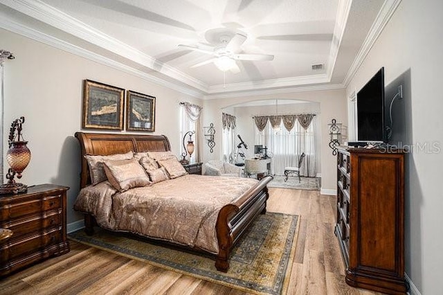 bedroom featuring baseboards, visible vents, arched walkways, ornamental molding, and wood finished floors