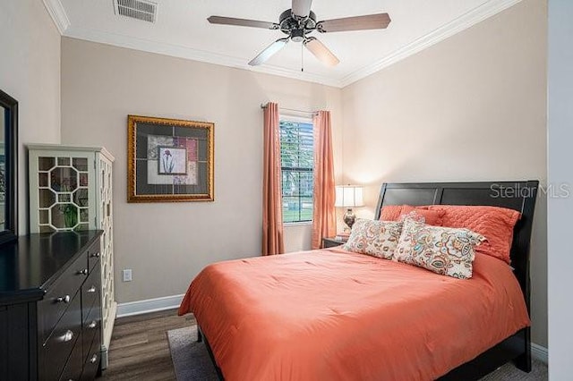 bedroom with visible vents, dark wood finished floors, a ceiling fan, baseboards, and ornamental molding