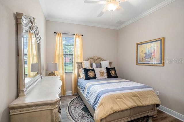 bedroom featuring a ceiling fan, crown molding, baseboards, and wood finished floors