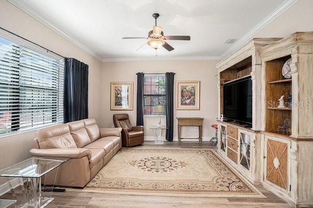 living room featuring ornamental molding, ceiling fan, baseboards, and wood finished floors