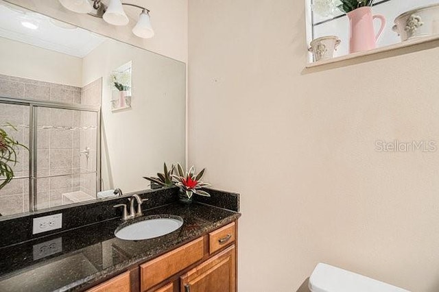 full bath featuring tiled shower, vanity, and toilet