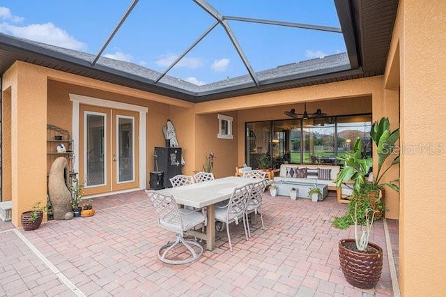 view of patio / terrace with ceiling fan, glass enclosure, french doors, and outdoor dining space