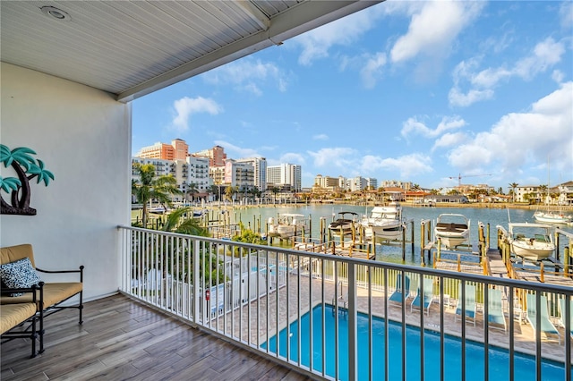 balcony featuring a boat dock, a water view, boat lift, and a city view