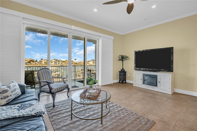 living area with ornamental molding, a ceiling fan, baseboards, and tile patterned floors