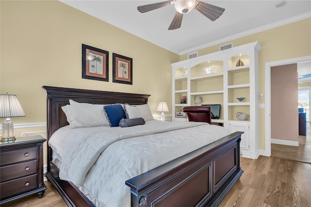 bedroom with light wood finished floors, visible vents, and crown molding