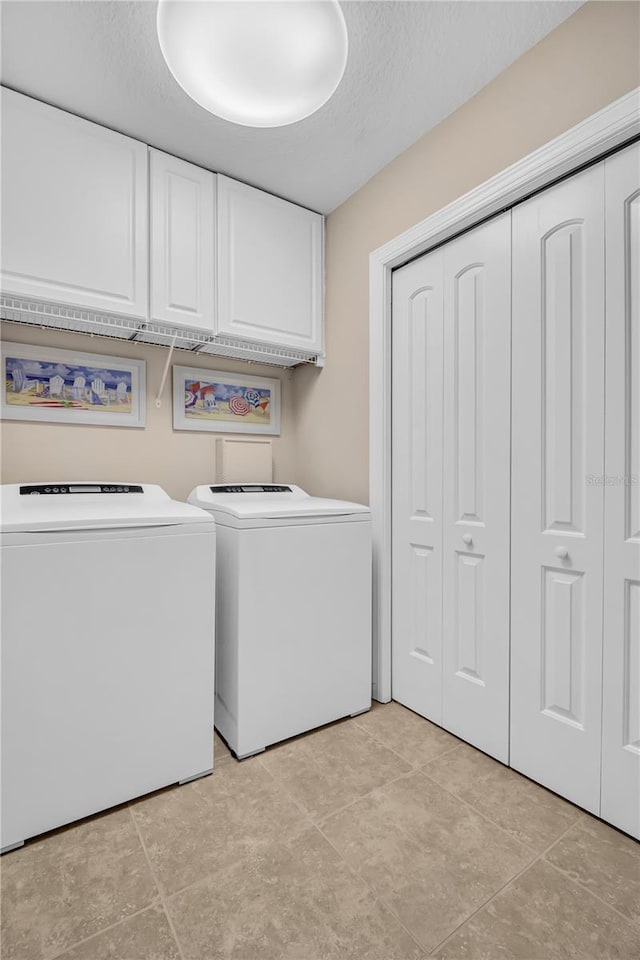 laundry room with a textured ceiling, independent washer and dryer, and cabinet space