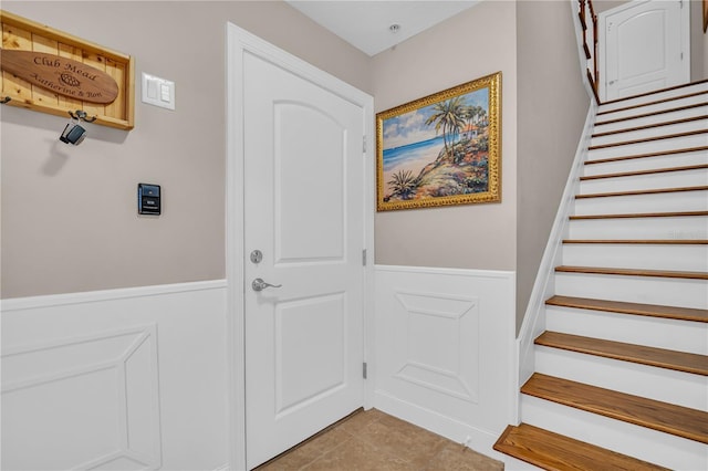 staircase with tile patterned flooring and wainscoting