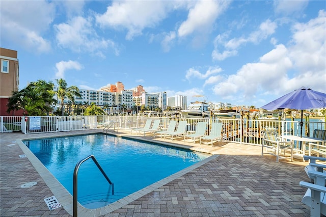 community pool featuring a patio, fence, and a city view