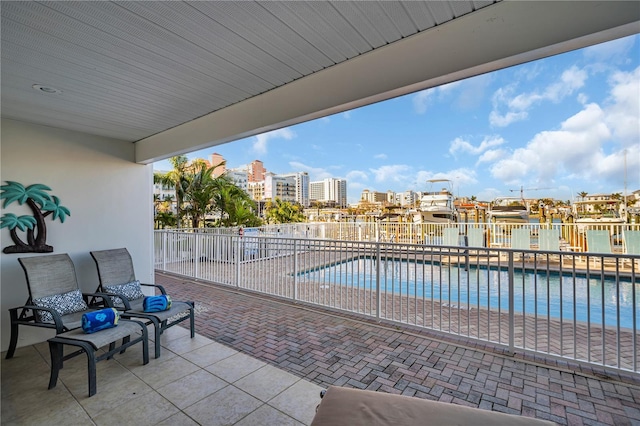 community pool featuring a patio area, fence, and a city view