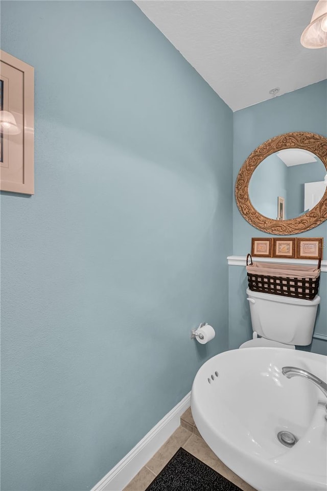 half bath featuring tile patterned flooring and baseboards