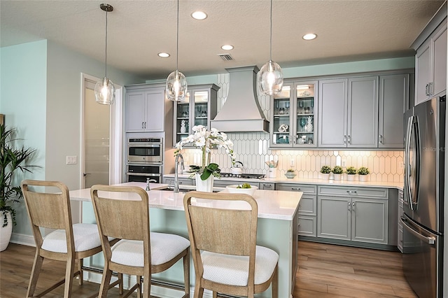 kitchen featuring appliances with stainless steel finishes, gray cabinets, and custom exhaust hood