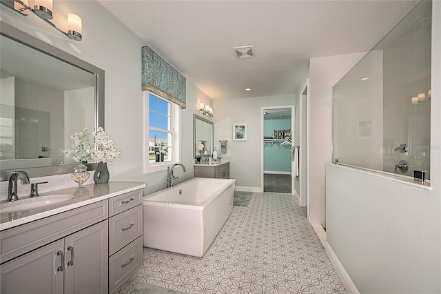 bathroom with two vanities, a sink, baseboards, a freestanding bath, and a tile shower